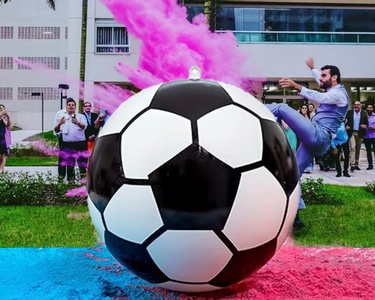 Iemand schopt een gender reveal voetbal met een roze poederwolk in de lucht